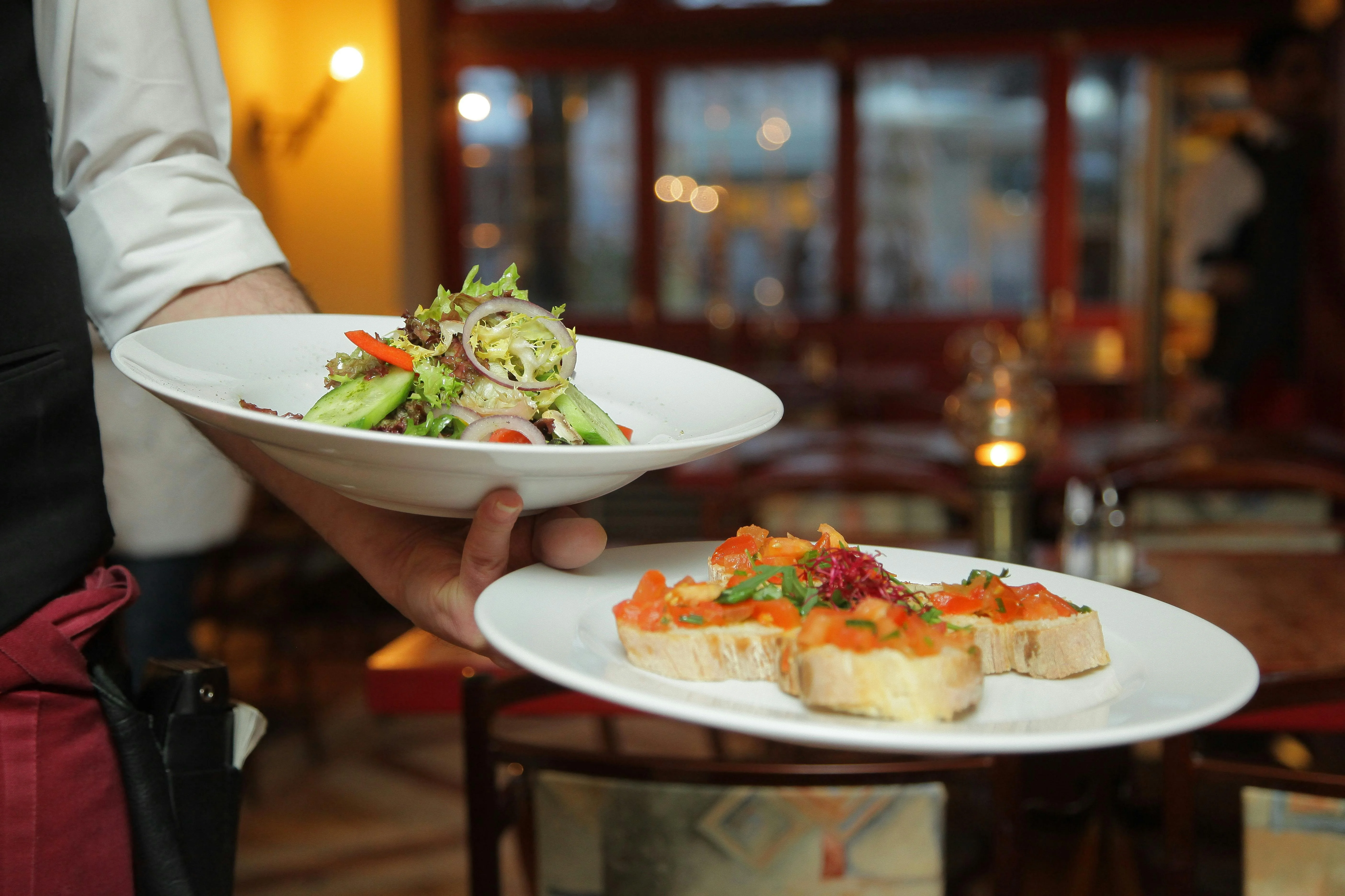 Luxury hotel reception staff and restaurant server presenting fine dining dishes.